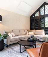 Sala moderna en Résidence Lage Vuursche, Utrecht, con sofá en L, ventanales grandes y plantas verdes.