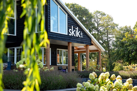 Vista frontal de skik&zo en Résidence Lichtenvoorde, rodeado de flores y vegetación en Gelderland, Países Bajos.