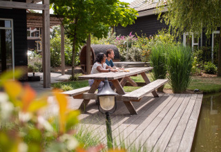 Deux personnes à une table de pique-nique près de l'eau à Résidence Lichtenvoorde, sous le soleil de Gelderland.
