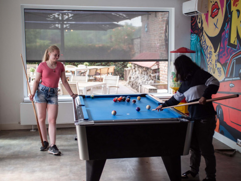Dos jóvenes juegan al billar en una mesa de pool en el parque vacacional Résidence Valkenburg en Limburgo, Países Bajos.