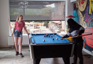Twee jongeren spelen biljart op een pooltafel in Résidence Valkenburg, vakantiepark in Limburg, Nederland.