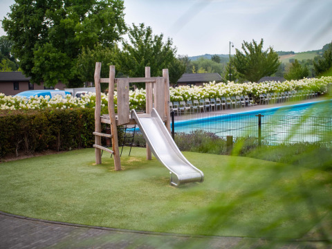 Parque infantil con tobogán junto a piscina en Résidence Valkenburg, parque vacacional en Limburgo, Países Bajos.