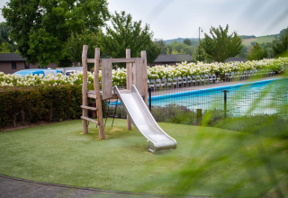 Parque infantil con tobogán junto a piscina en Résidence Valkenburg, parque vacacional en Limburgo, Países Bajos.