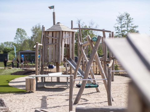 Parque infantil de madera con tobogán y columpio en Résidence Valkenburg, Limburg, Países Bajos, de día.
