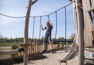 Kind balanciert auf einer Hängebrücke auf dem Spielplatz im Ferienpark Résidence Valkenburg in Limburg, Niederlande.