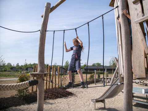 Kind balanciert auf einer Hängebrücke auf dem Spielplatz im Ferienpark Résidence Valkenburg in Limburg, Niederlande.