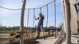 Niño cruza un puente de cuerda en el parque infantil al aire libre de Résidence Valkenburg en Limburg, Países Bajos.