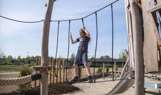 Kind balanciert auf einer Hängebrücke auf dem Spielplatz im Ferienpark Résidence Valkenburg in Limburg, Niederlande.