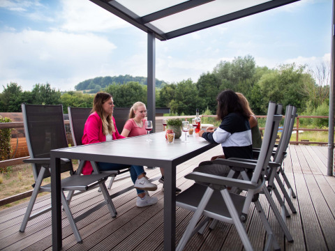Vier mensen aan een tafel op een overdekt terras bij Résidence Valkenburg, een vakantiepark in Limburg, Nederland.