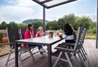 Vier mensen aan een tafel op een overdekt terras bij Résidence Valkenburg, een vakantiepark in Limburg, Nederland.