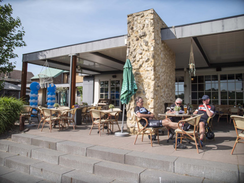 Cyclists relaxing on the terrace at Résidence Valkenburg holiday park in Limburg, Netherlands, sunny day.