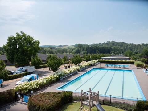 Outdoor swimming pool at Résidence Valkenburg holiday park, surrounded by greenery and hills in Limburg, Netherlands.