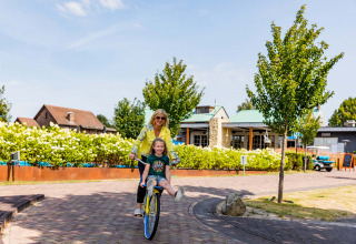 Mutter und Tochter fahren Fahrrad in Résidence Valkenburg, einem Ferienpark in Limburg, Niederlande.
