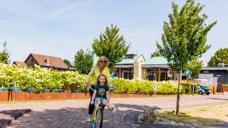 Madre e hija disfrutan andando en bicicleta en Résidence Valkenburg, un parque vacacional en Limburg, Países Bajos.