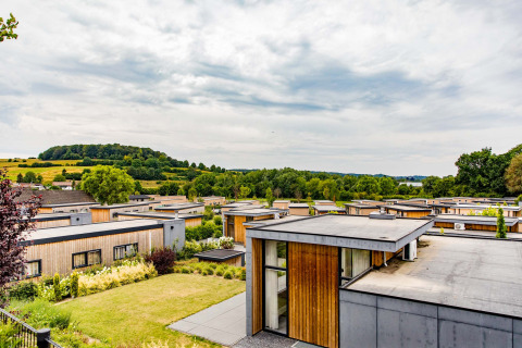 Flat-roof modern holiday bungalows at Résidence Valkenburg, Limburg, Netherlands, with green hills nearby.