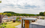 Bungalows med fladt tag omgivet af grøn natur og bakker i Résidence Valkenburg, Limburg, Holland.