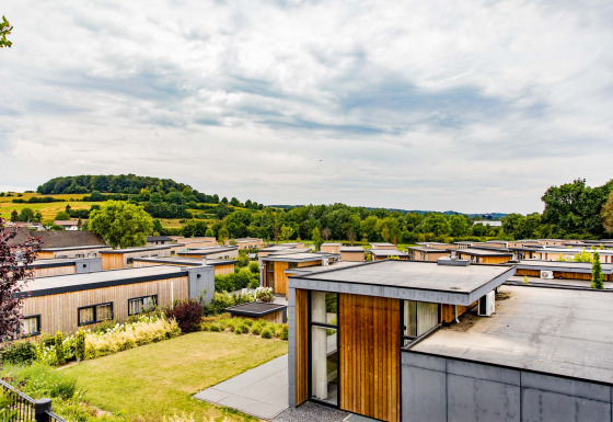 Flat-roof modern holiday bungalows at Résidence Valkenburg, Limburg, Netherlands, with green hills nearby.