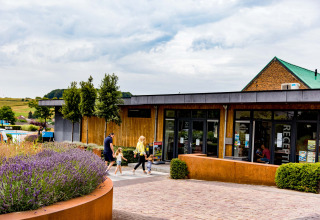Family walking past the reception at Résidence Valkenburg holiday park in Limburg, Netherlands, with gardens.