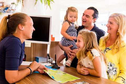 Eine Familie informiert sich an der Rezeption des Ferienparks Résidence Valkenburg in Limburg, Niederlande.
