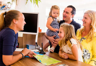 Una famiglia riceve informazioni alla reception del parco vacanze Résidence Valkenburg in Limburg, Paesi Bassi.