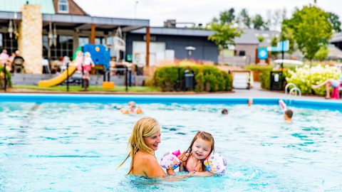 Mutter und Tochter genießen den Pool im Ferienpark Résidence Valkenburg in Limburg, Niederlande, bei Sonne.