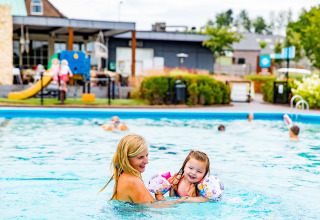 Moeder en dochter spelen in het buitenzwembad van vakantiepark Résidence Valkenburg in Limburg, Nederland.