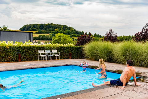 Family enjoying time by an outdoor pool at Résidence Valkenburg, surrounded by Limburg's scenic countryside.