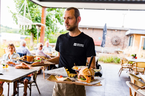Een ober draagt eten op het terras van Résidence Valkenburg, een vakantiepark in Limburg, Nederland.