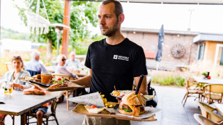 Un camarero lleva comida en la terraza de Résidence Valkenburg, un parque de vacaciones en Limburgo, Países Bajos.