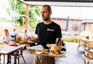 Un cameriere porta cibo sulla terrazza di Résidence Valkenburg, un parco vacanze in Limburgo, Paesi Bassi.