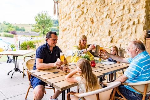 Familia disfrutando de bebidas en la terraza de Résidence Valkenburg, parque vacacional en Limburg, Países Bajos.