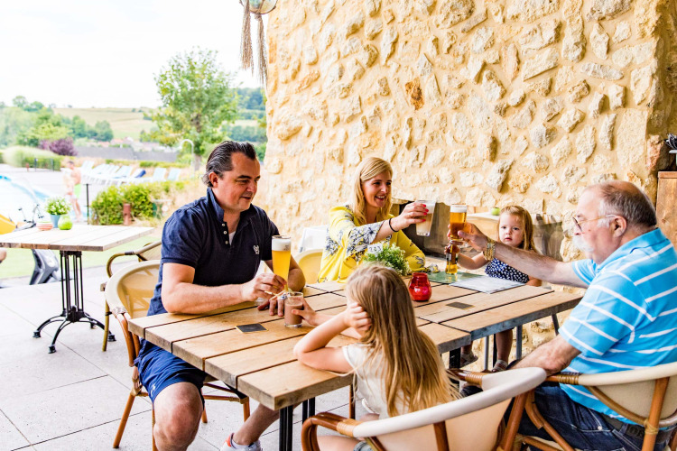 Famille profitant de boissons sur la terrasse de Résidence Valkenburg, parc de vacances à Limbourg, Pays-Bas.