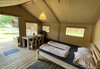 Indvendigt billede af Safari telt på Camping du Rivage i Luxembourg, med seng, bord og træterrasse.