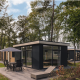 Moderne sort Kubus Lodge med sauna i skovområdet ved Holiday Park De Lochemse Berg, Nederlandene.