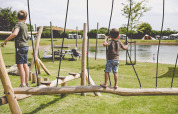 Due bambini giocano su un parco giochi di legno vicino a un lago al Camping de Bovenberg a Overijssel, Paesi Bassi.