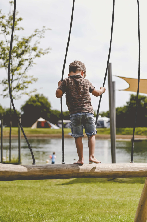 Bambino che gioca su un ponte di legno al lago al Camping de Bovenberg, Overijssel, Paesi Bassi.