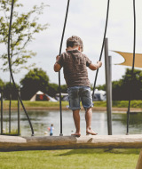 Niño jugando en un puente de madera sobre el lago en Camping de Bovenberg, Overijssel, Países Bajos.