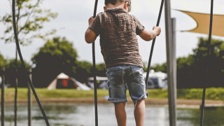 Kind speelt op houten brug bij het meer op Camping de Bovenberg, vakantiepark in Overijssel, Nederland.