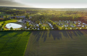 Vista aerea di Camping de Bovenberg a Overijssel, Paesi Bassi, con roulotte, stagno e campi verdi.