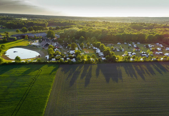 Aerial view of Camping de Bovenberg in Overijssel, Netherlands, with caravans, pond, and green fields.
