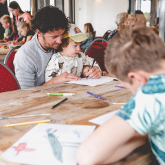 Kinderen en volwassenen doen mee aan knutselactiviteiten op Camping de Bovenberg in Overijssel, Nederland.