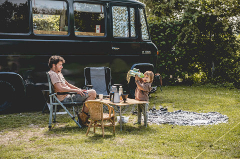 Un uomo e un bambino campeggiano accanto a un furgone nero a Camping de Bovenberg, Overijssel, Paesi Bassi.