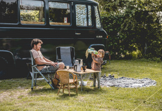 Un uomo e un bambino campeggiano accanto a un furgone nero a Camping de Bovenberg, Overijssel, Paesi Bassi.