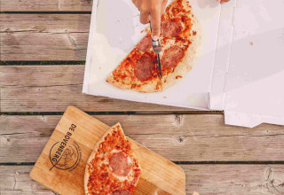 Two people enjoying pizza on a wooden table at Camping de Bovenberg, a holiday park in Overijssel, Netherlands.