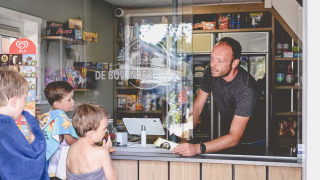 Kinderen in handdoeken kopen ijs bij de kiosk van Camping de Bovenberg in Overijssel, Nederland.