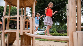 Niños juegan en un parque infantil de madera en Resort Veluwe, parque vacacional en Gelderland, Países Bajos.