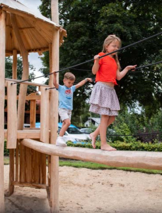 Niños juegan en un parque infantil de madera en Resort Veluwe, parque vacacional en Gelderland, Países Bajos.