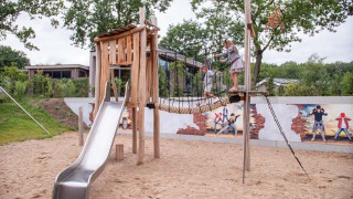 Parque infantil con tobogán, puente de cuerda y mural en Recreatiepark Beekbergen, parque vacacional en Gelderland, Países Bajos.