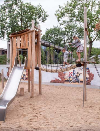Parque infantil con tobogán, puente de cuerda y mural en Recreatiepark Beekbergen, parque vacacional en Gelderland, Países Bajos.
