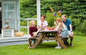 Familie nyder måltid udendørs ved et bord foran Verandah Chalet på Camping Sevink Molen, Holland.